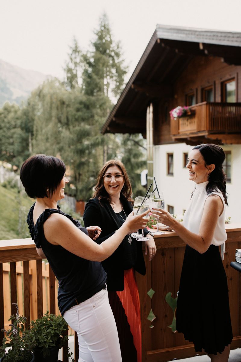 Drei Frauen stoßen auf einem Balkon an