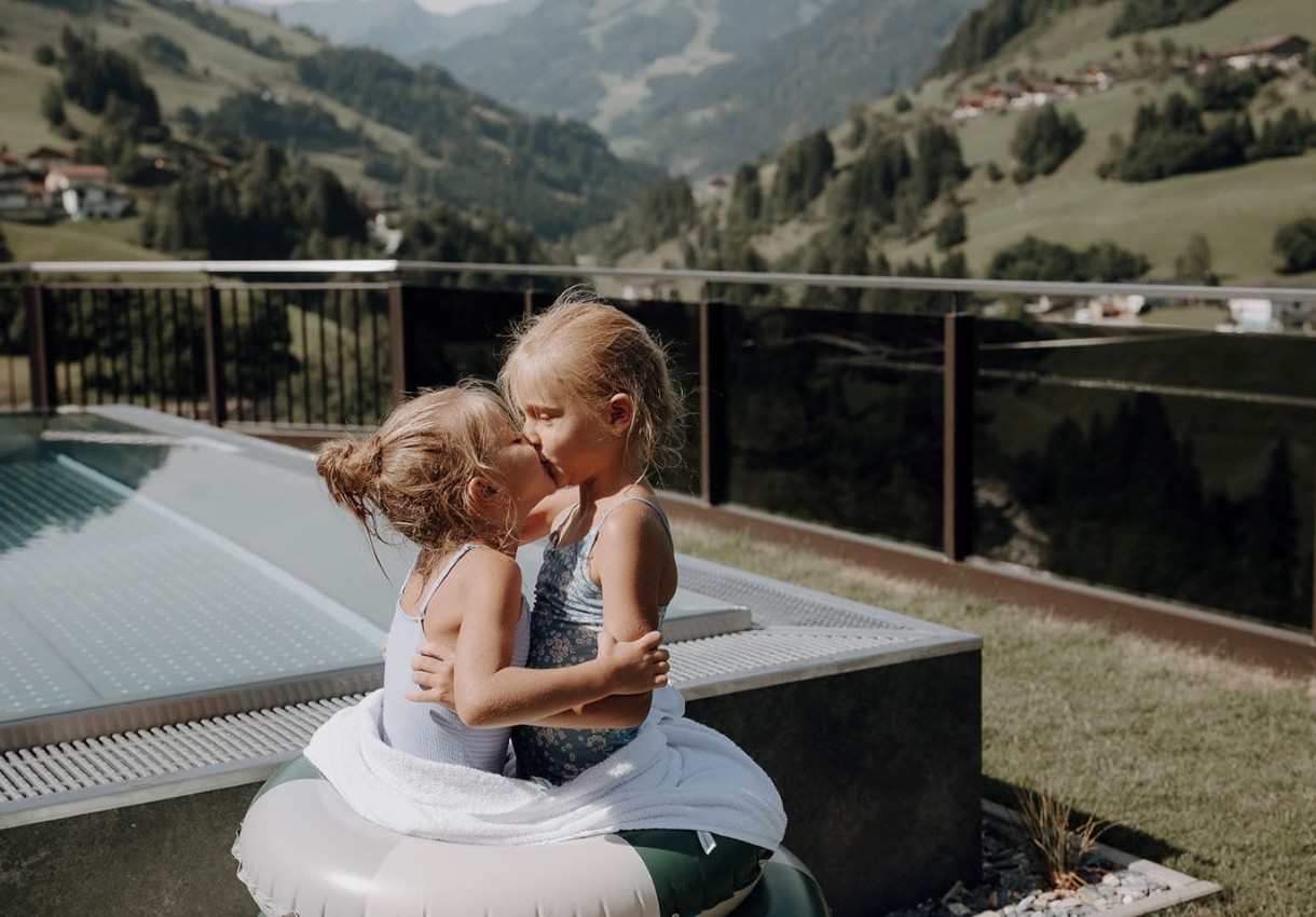 Zwei Kinder umarmen sich vor einer Bergkulisse