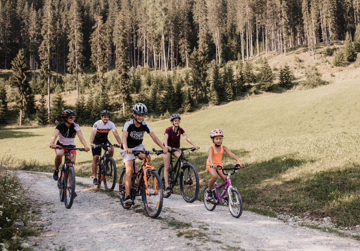 Familie fährt mit Fahrrädern auf einem Waldweg