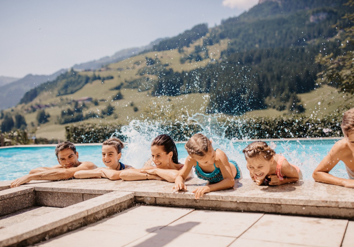Familie planscht am Pool mit Bergblick im Hotel Dorfer