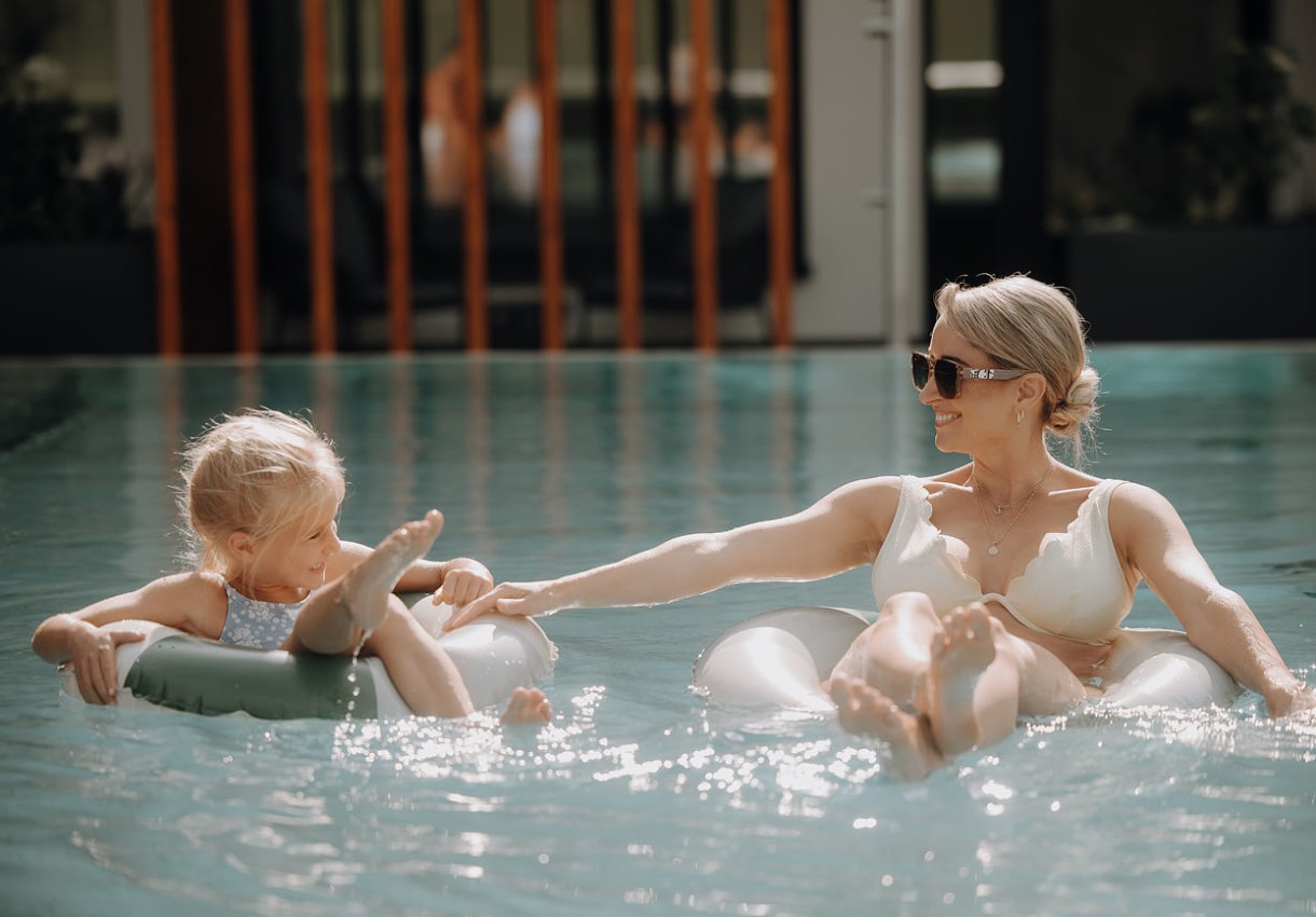 Mama und Kind mit Reifen im Pool mit Bergblick im Hotel Dorfer
