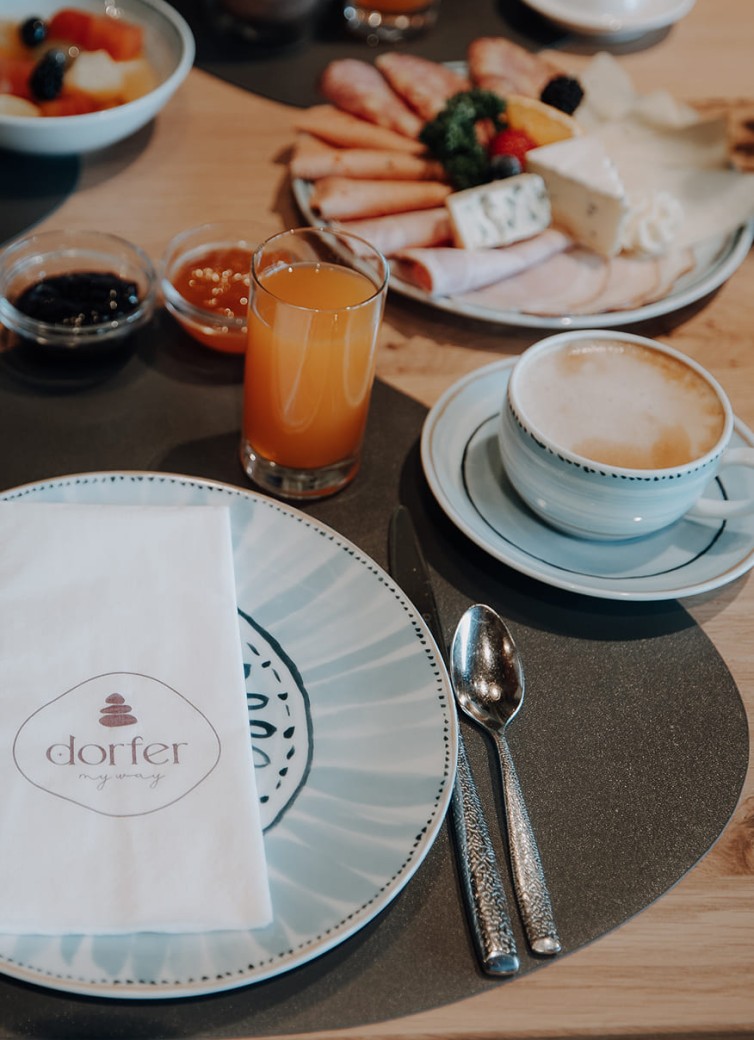 Dorfer-Frühstückstisch mit Kaffee, Saft, Aufschnitt, Käse und Marmelade
