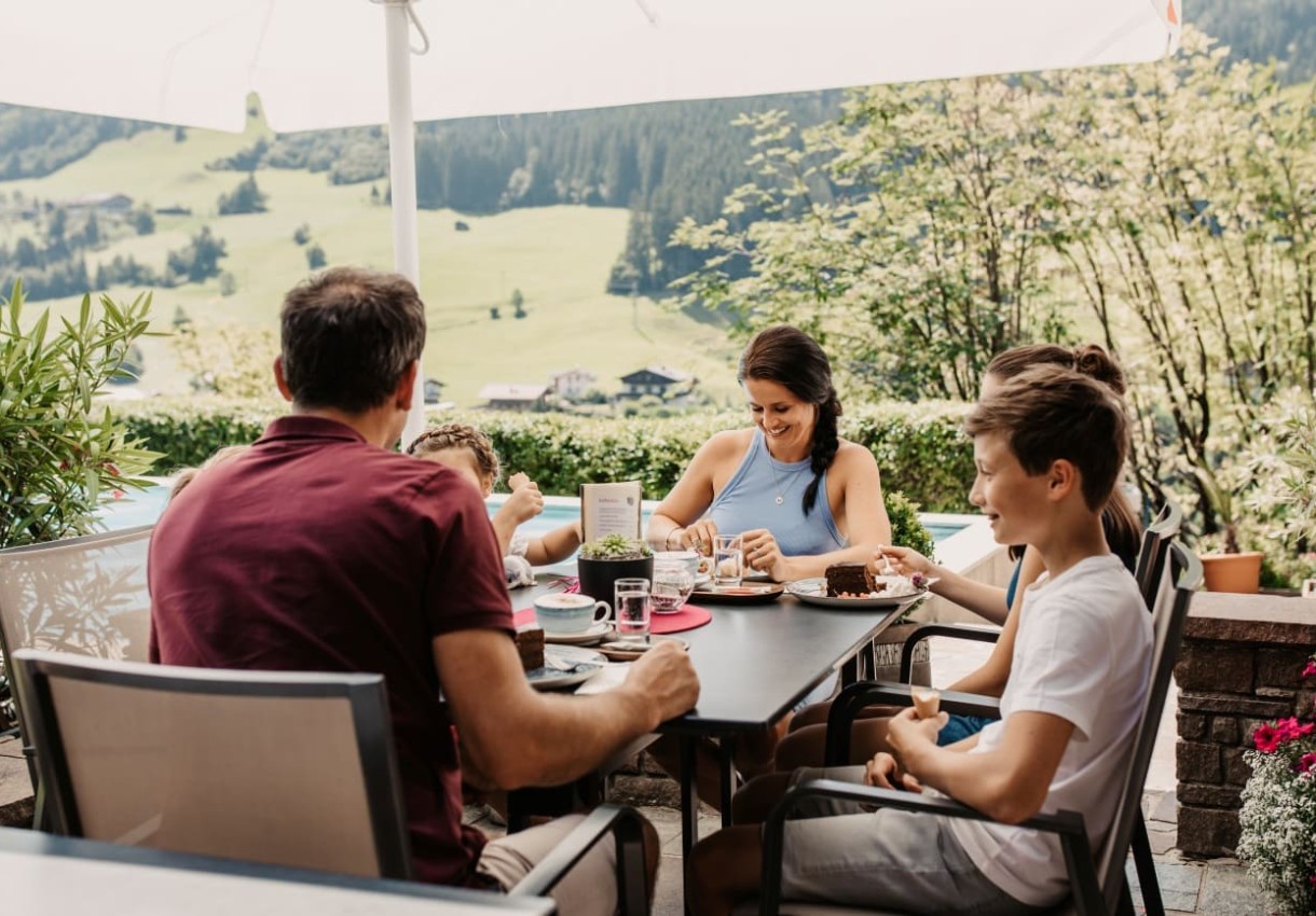 Familie beim Kuchen essen auf der Sonnenterrasse am Nachmittag