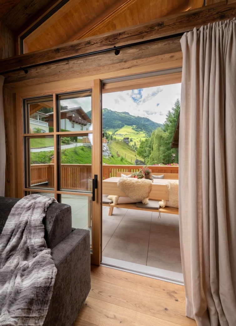 Sicht durch Terrassentüren auf gemütliche Sitzbank mit Bergblick im Hintergrund