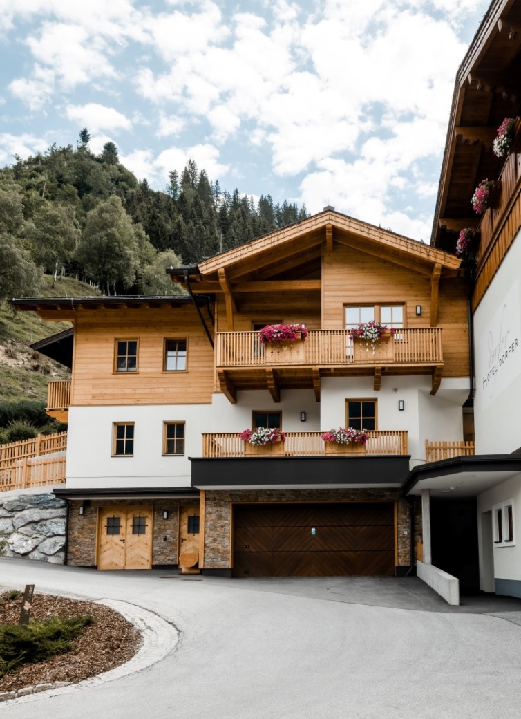 Hotel Dorfer mit Balkonen und Blumendekorationen vor bewaldeten Hügeln