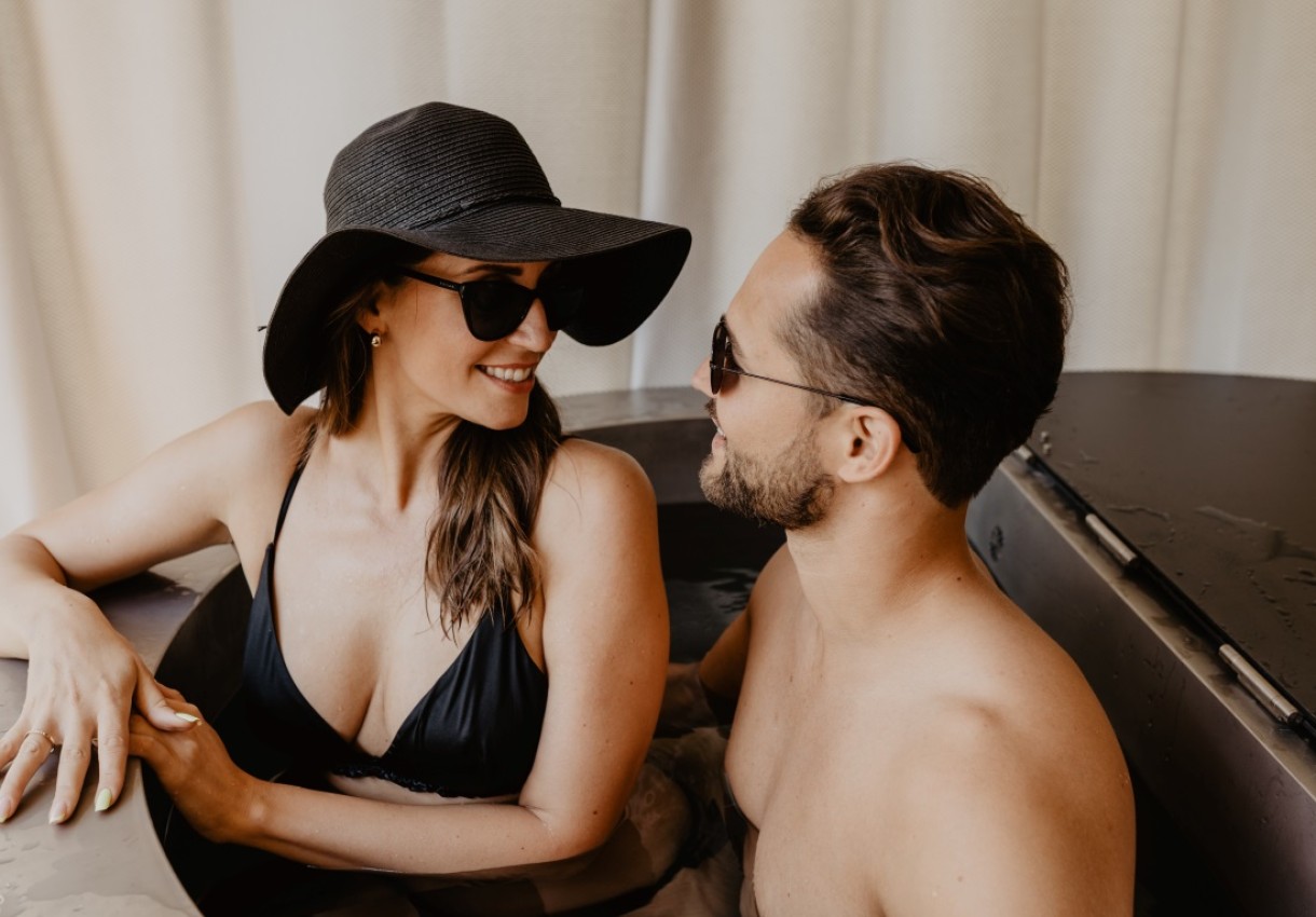 Ein Paar entspannt lächelnd in einem Whirlpool, beide tragen Sonnenbrillen