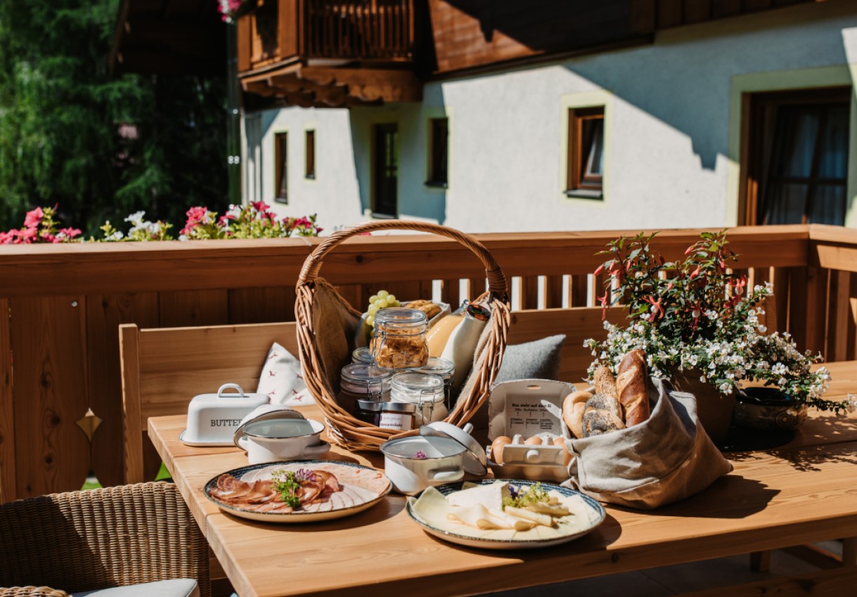 Ein Frühstückstisch auf einer Terrasse mit Brot, Käse und Aufschnitt