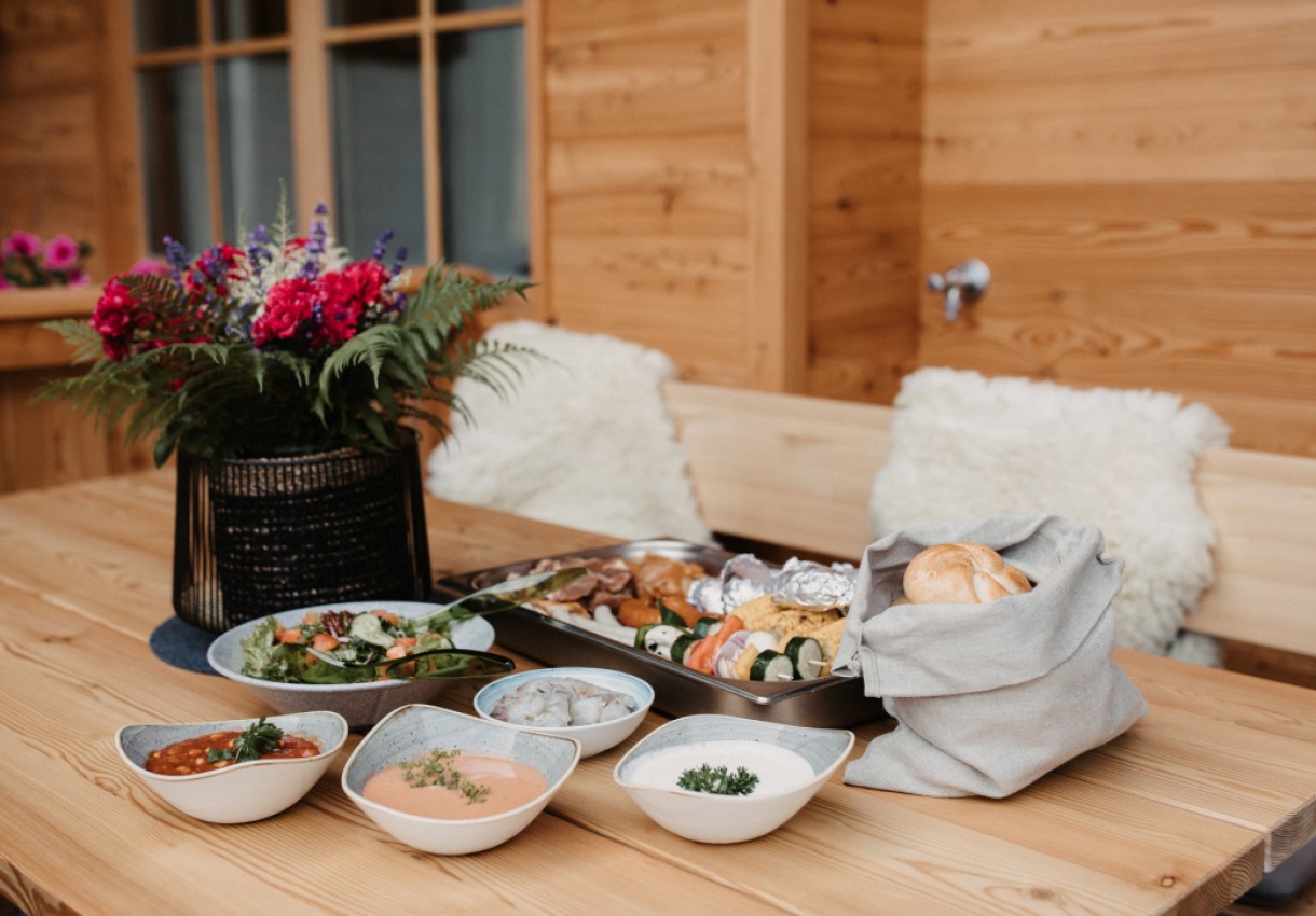 Ein Holztisch mit verschiedenen Speisen und einem Blumenarrangement darauf