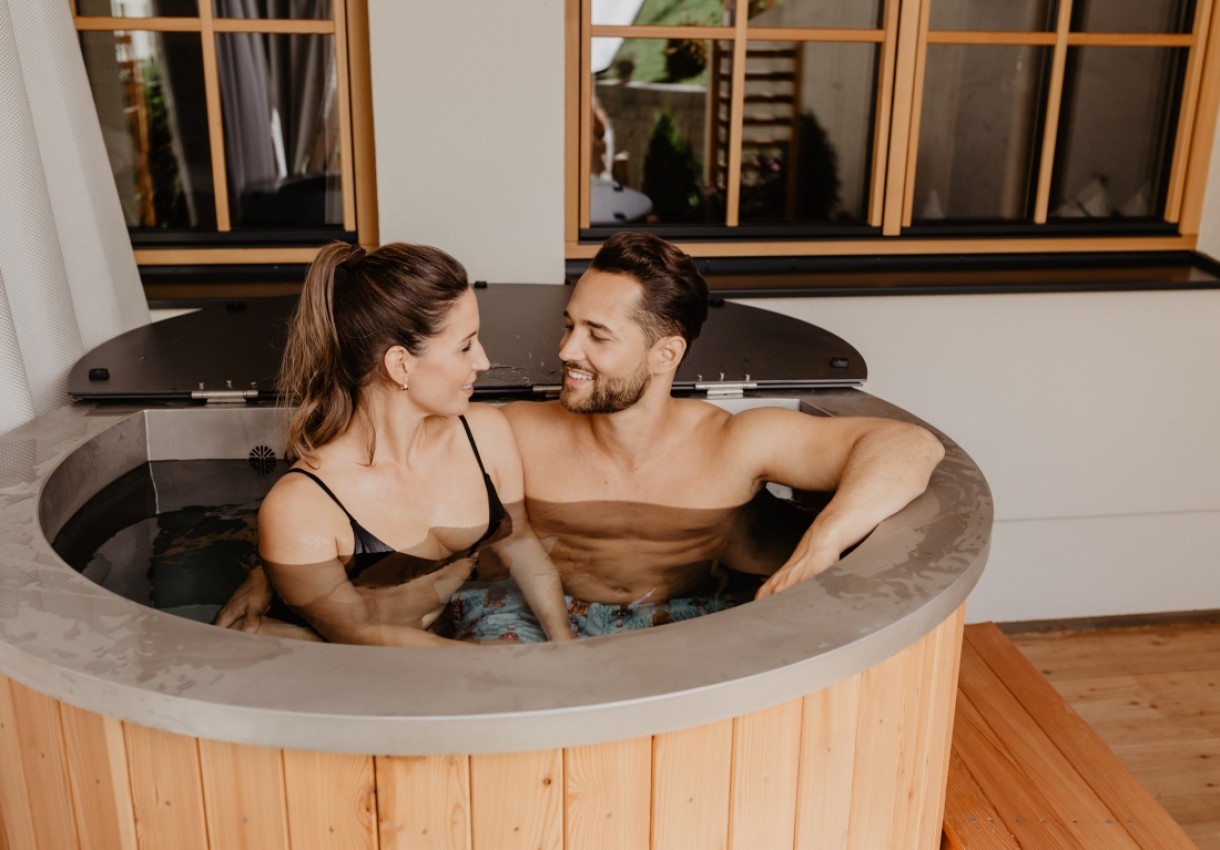 Ein Paar entspannt sich in einem runden Whirlpool auf einer Terrasse