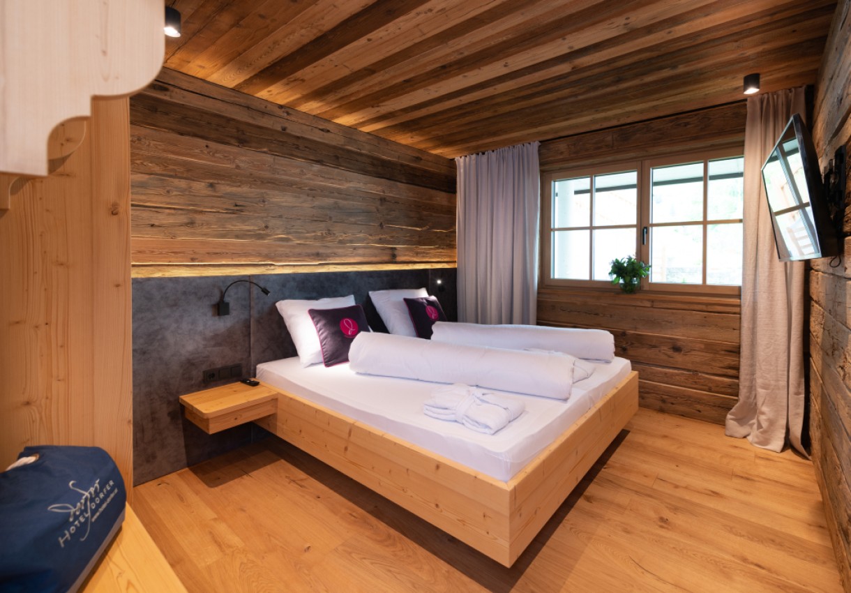 Gemütliches Schlafzimmer aus Holz mit großem Bett und Flachbildfernseher