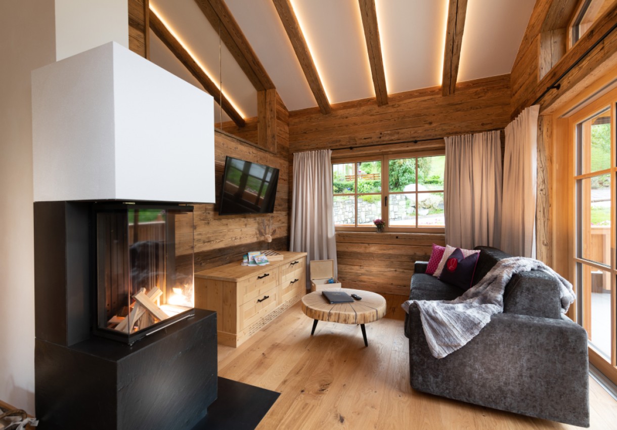 Gemütliches Wohnzimmer mit Kamin, Holzdekor und großen Fenstern