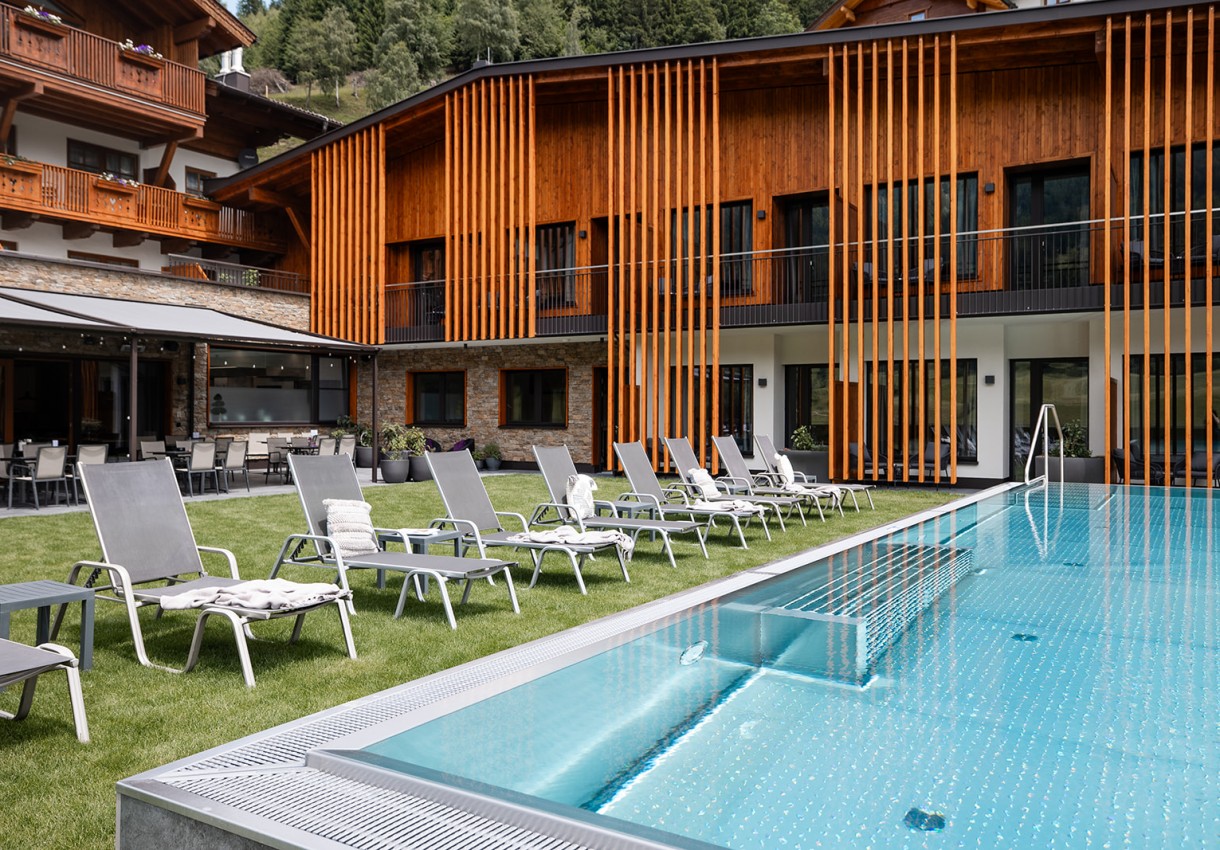 Moderner Poolbereich mit Sonnenliegen in alpiner Umgebung