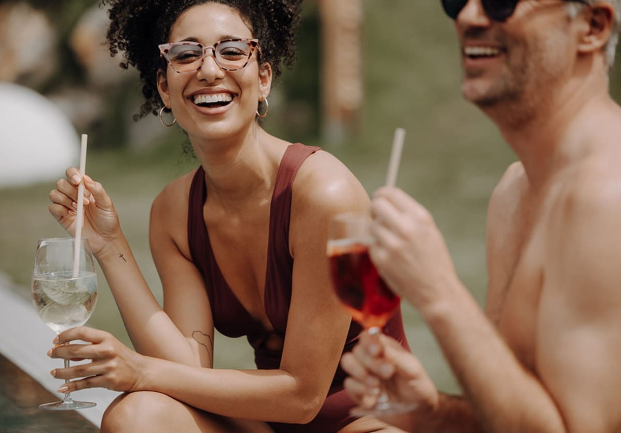 P&auml;rchen lacht und trinkt Cocktails am Pool