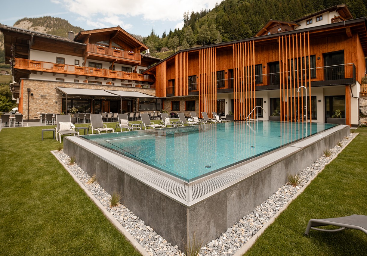 Hotel Dorfer in Großarl mit Pool und Liegestühlen vor einer Bergkulisse