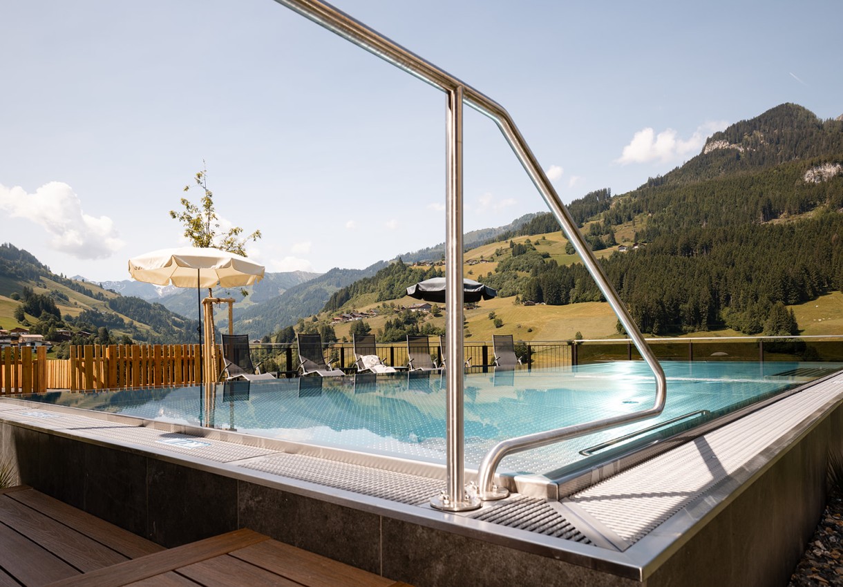 Ein Pool mit Bergblick, Sonnenschirmen und Liegestühlen im Hintergrund