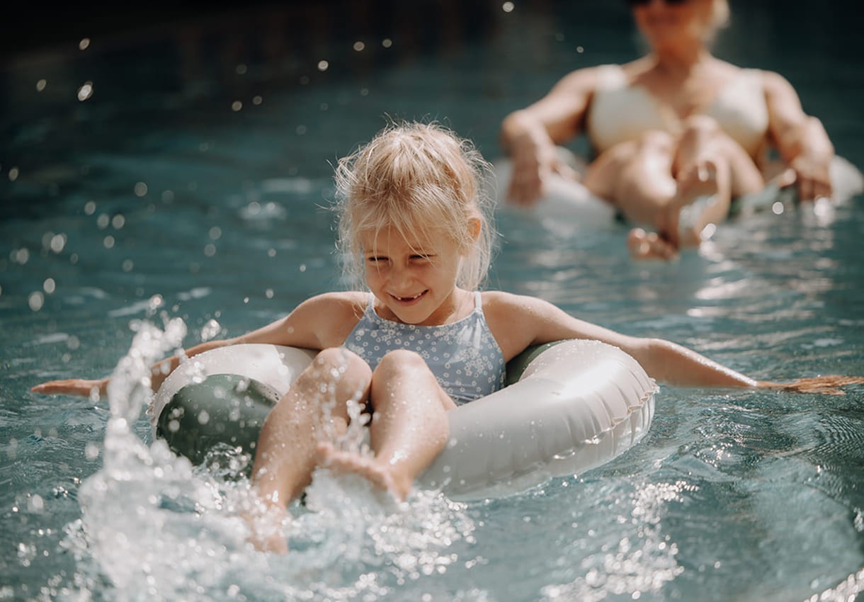 Ein l&auml;chelndes M&auml;dchen planscht fr&ouml;hlich im Pool auf einem Schwimmring