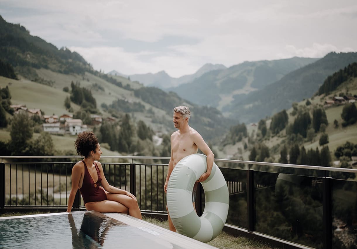 Ein Paar entspannt sich am Pool mit Bergblick im Hintergrund
