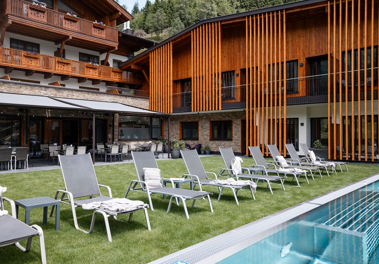 Hotel Dorfer mit moderner Architektur, Sonnenliegen auf Rasen vor einem Pool platziert