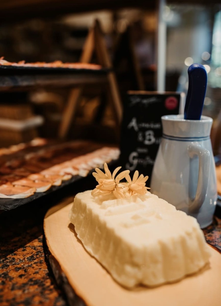 Butterstück mit Blumenverzierung und blauem Krug im Hintergrund auf einem Tisch
