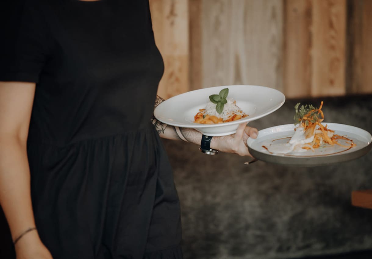 Kellnerin serviert zwei Teller mit dekorativen Gerichten