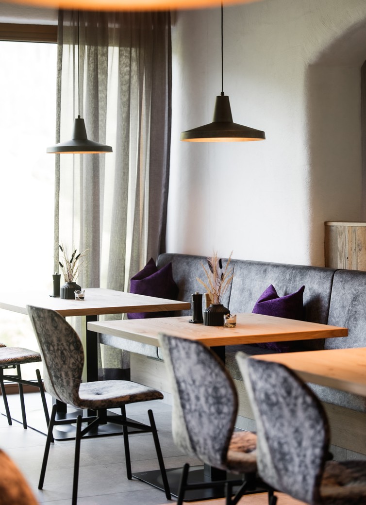 Restaurant-Einrichtung mit Holztischen, Stühlen und violetten Kissen