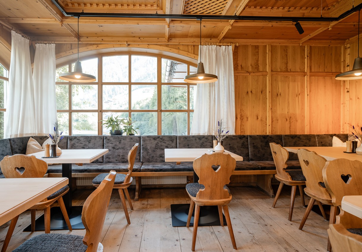 Restaurant mit Holzmöbeln, großen Fenstern und Sitzbank