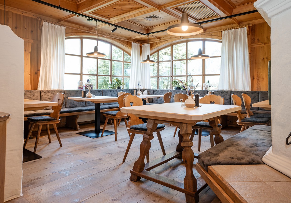 Gemütliches Restaurant mit Holzdekor und großen Fenstern, leeren Tischen und Stühlen