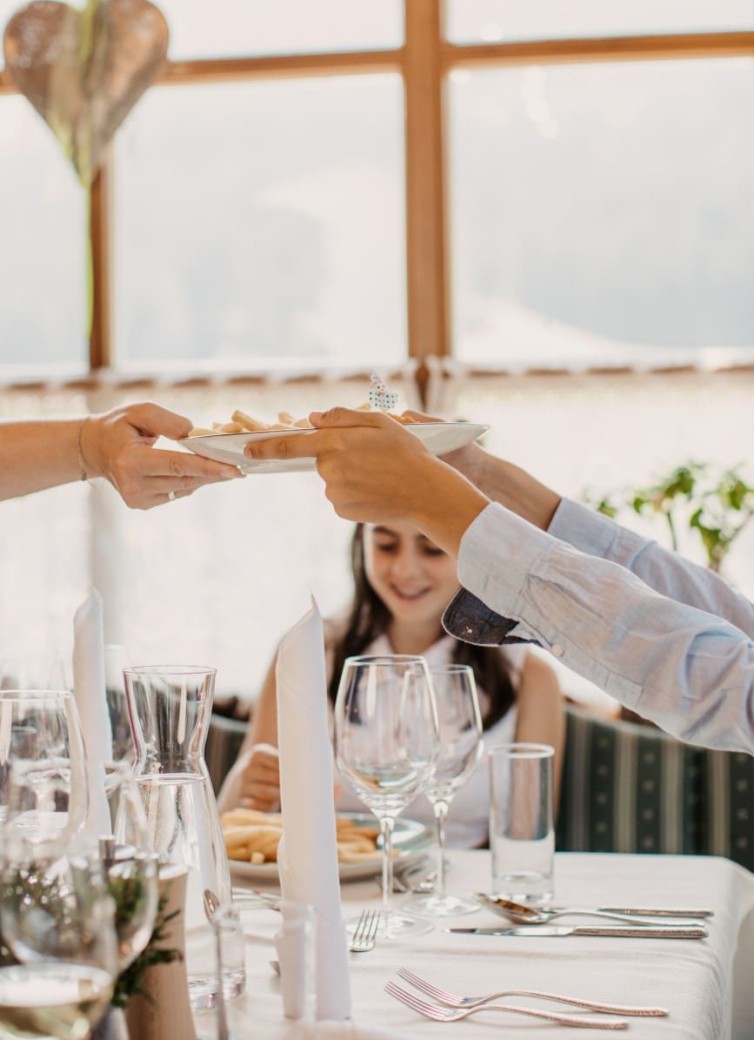 Zwei Personen tauschen einen Teller an einem festlich gedeckten Tisch aus