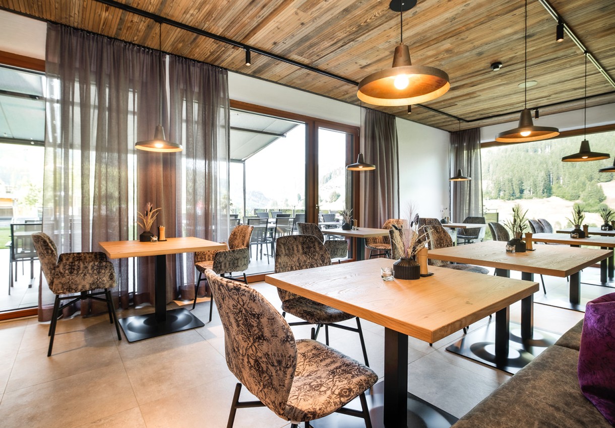 Restaurant vom Hotel Dorfer mit Holztischen und gepolsterten Stühlen in heller Umgebung