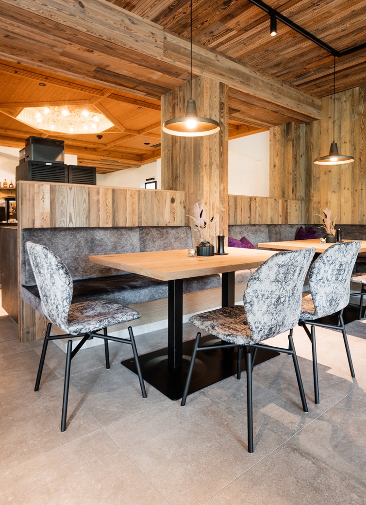 Essbereich mit Holzinterieur, grauen Polsterstühlen und einem Tisch unter Pendelleuchten