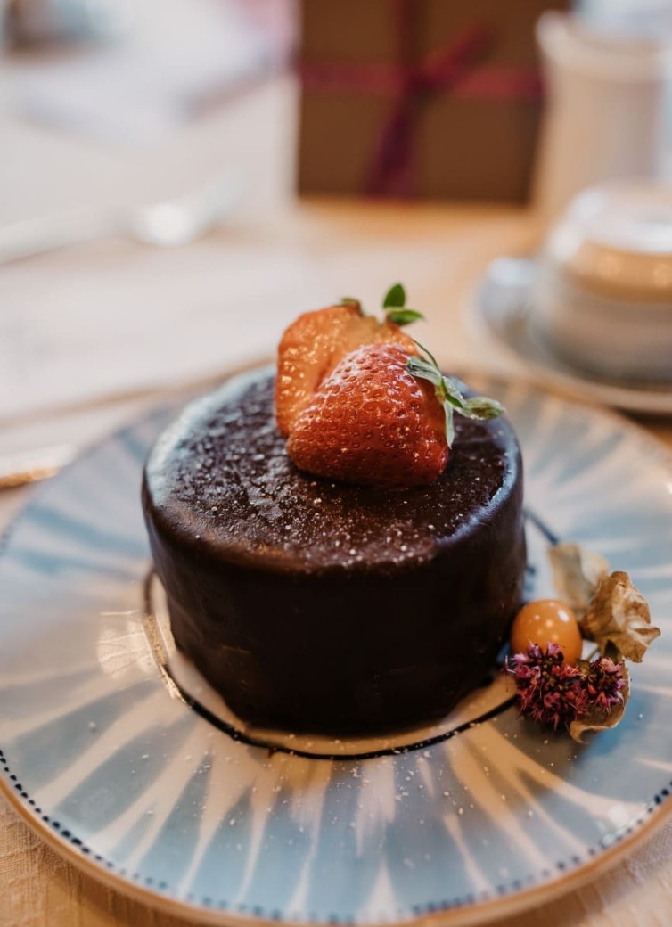 Kleiner Schokokuchen mit Erdbeeren und Blumen auf einem Teller