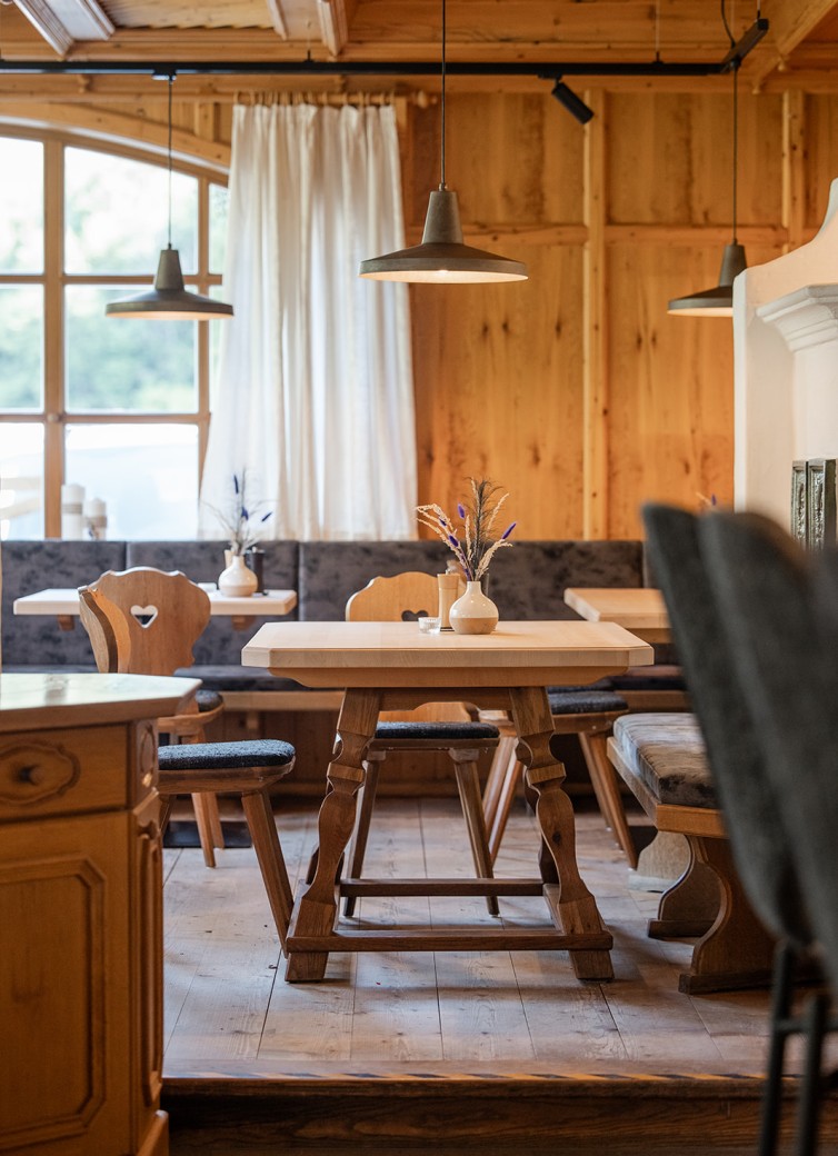 Gastraum vom Hotel Dorfer mit Holztischen, Sitzbänken und dekorativen Vasen
