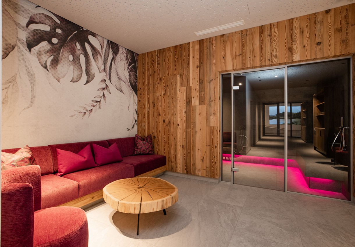 Gemütlicher Raum mit roten Möbeln, Holzwänden und einer Glastür zur Terrasse