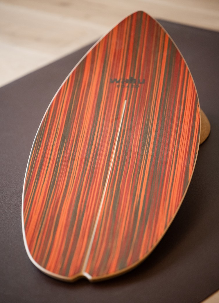 Ein Balanceboard mit rot-schwarzem Streifenmuster steht aufrecht auf dem Boden