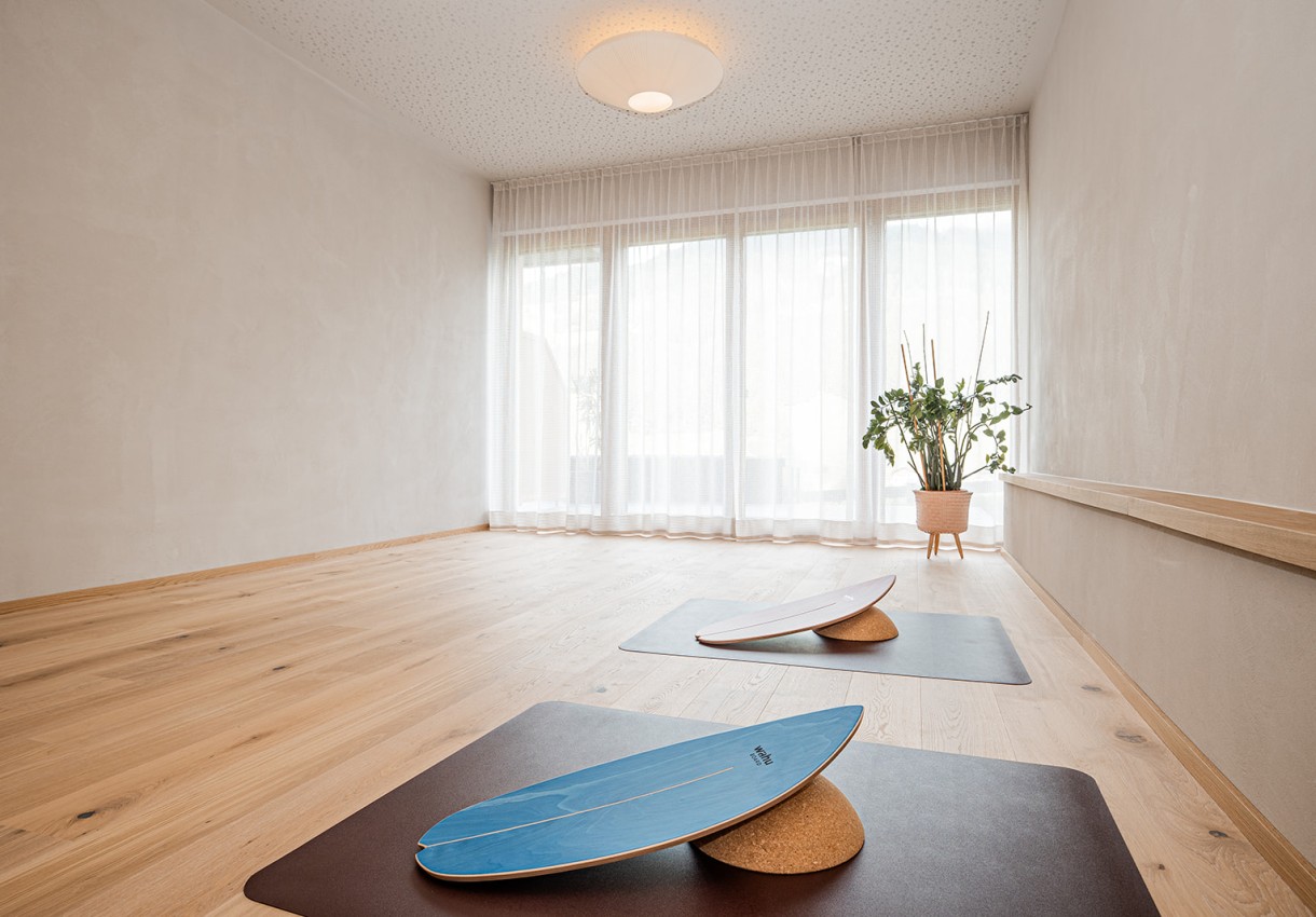 Wellnessbereich mit Holzboden, zwei Yoga-Matten und einem großen Fenster mit Vorhängen