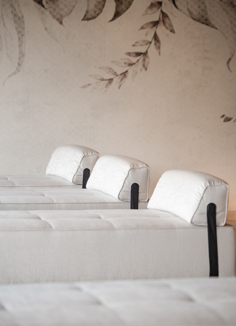 Reihe von hellen Lounge-Sesseln mit Kissen vor gemusterter Wand