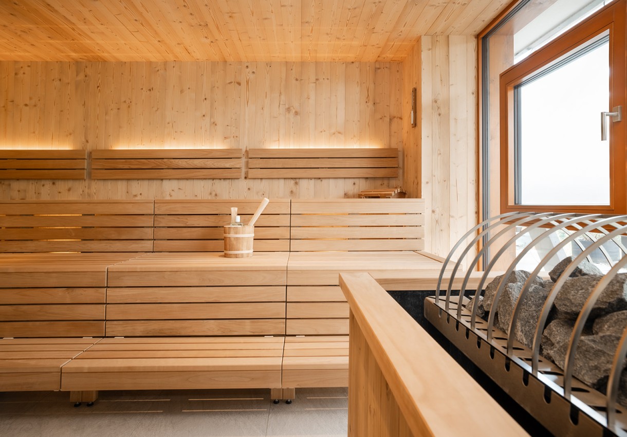 Moderne Holzsauna mit Sitzbänken und einem Eimer auf der Ablage
