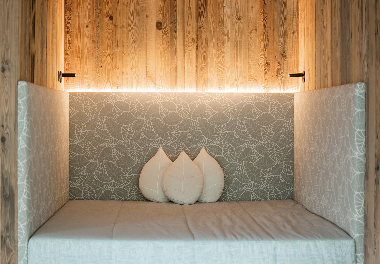 Gemütlicher Sitzbereich mit Holzwänden und Blätterkissen