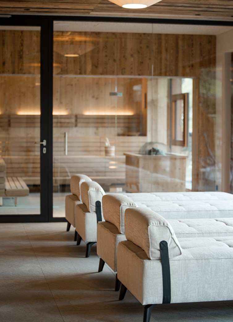Mehrere beige Liegen vor einer modernen, holzverkleideten Saunakabine