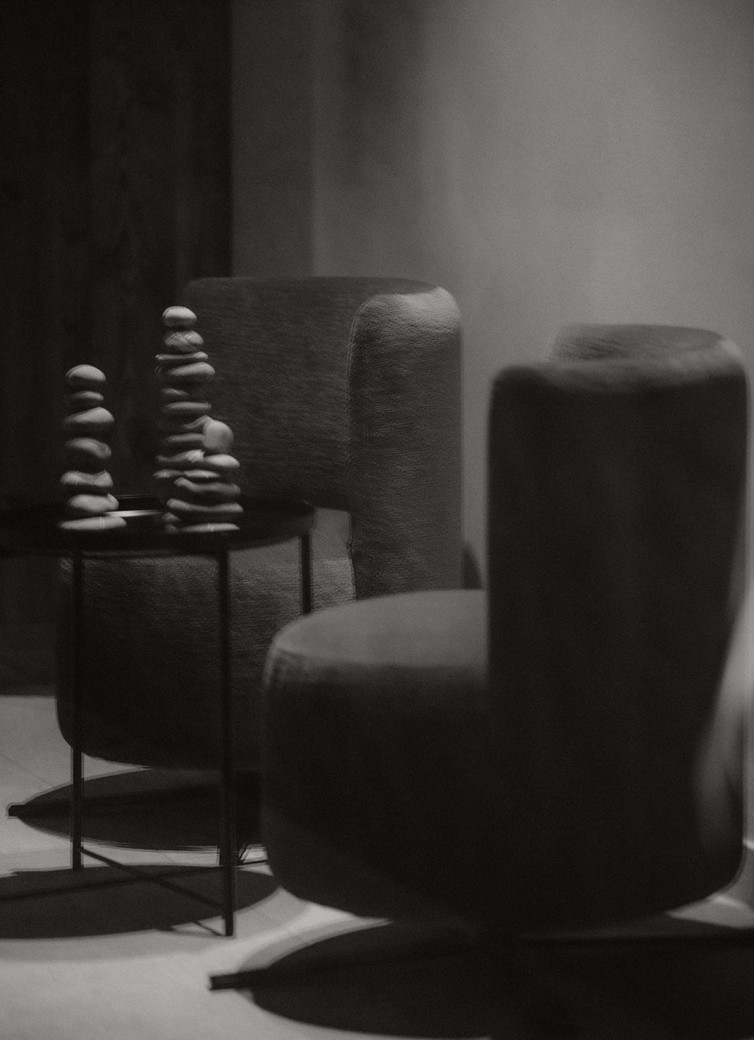 Zwei gepolsterte Stühle und ein Tisch mit gestapelten Steinen in einem minimalistischen Raum