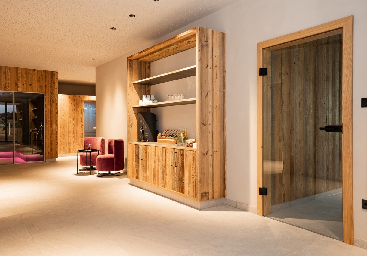 Moderne Lounge mit Holzwänden, roten Sesseln und einem Regal mit Kaffeemaschine