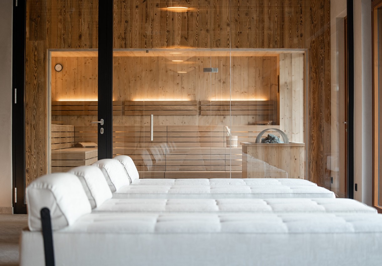 Moderne Sauna mit Holzverkleidung und weißen Ruheliegen davor