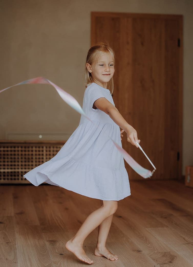 M&auml;dchen schwingt fr&ouml;hlich ein Band im Bewegungsraum