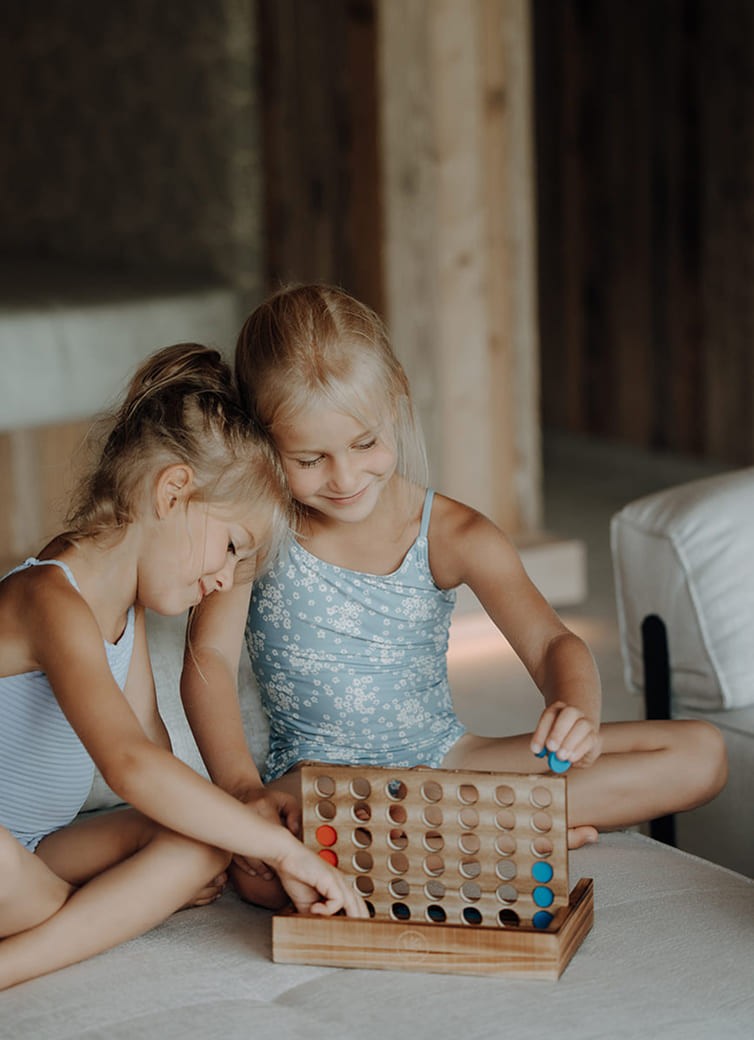 Zwei M&auml;dchen spielen ein Brettspiel auf einem Sofa