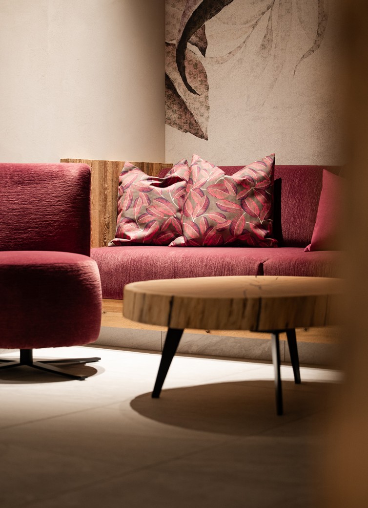 Roter Sessel und Sofa mit gemusterten Kissen neben einem runden Holztisch