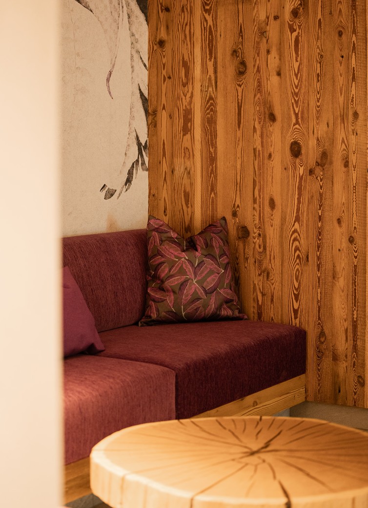 Ecke mit violettem Sofa, Holzwand und rundem Holztisch im gemütlichen Stil