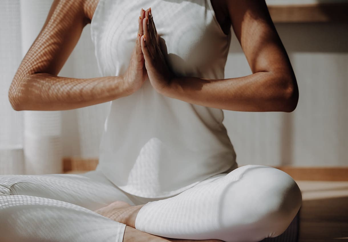 Eine Frau meditiert im Schneidersitz bei Sonnenlicht