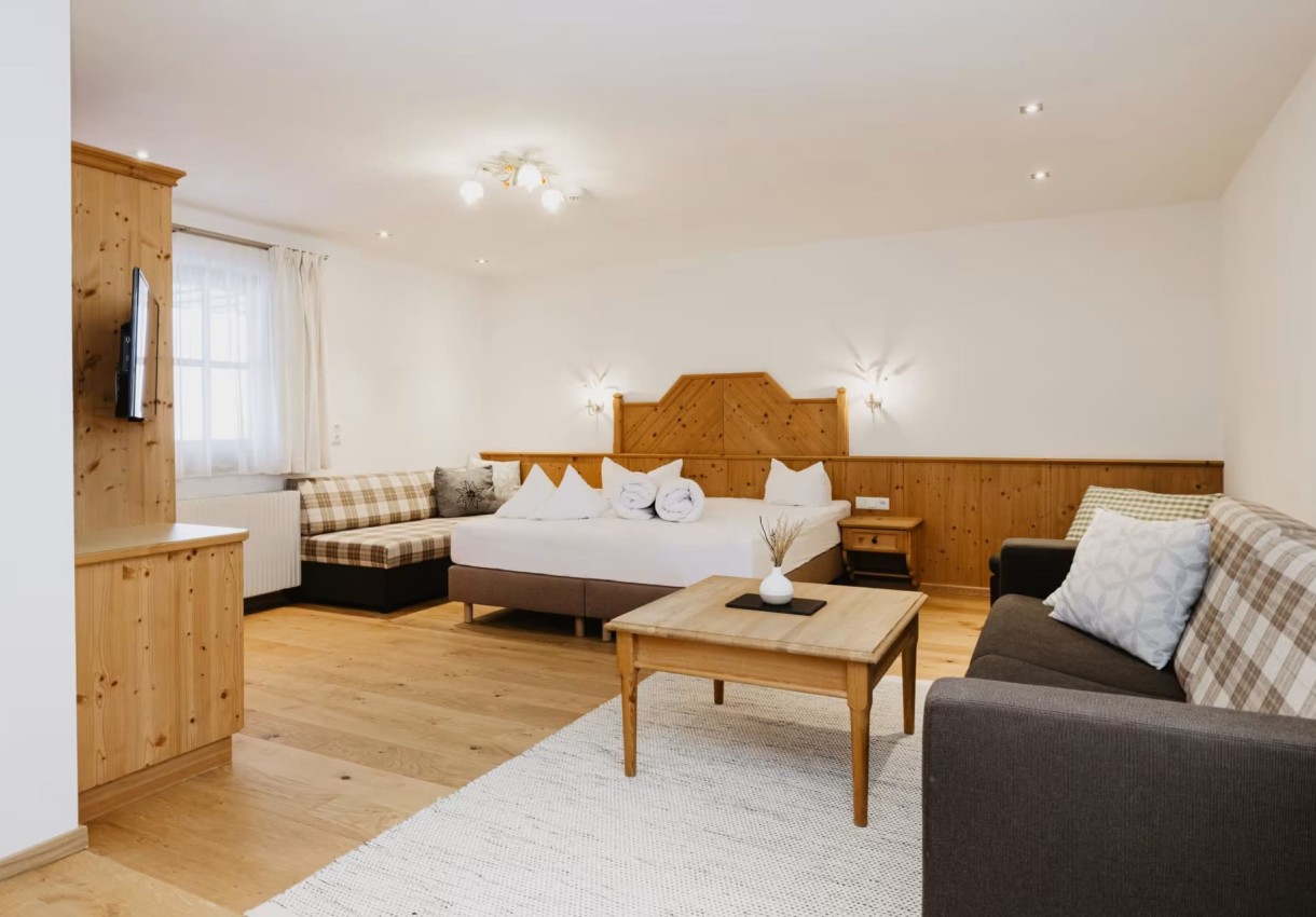 Gemütliches Hotelzimmer mit Doppelbett, Sofa und Holzdekor