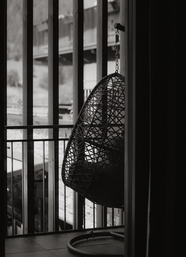 Ein Hängesessel auf einem Balkon mit Blick auf eine bergige Landschaft