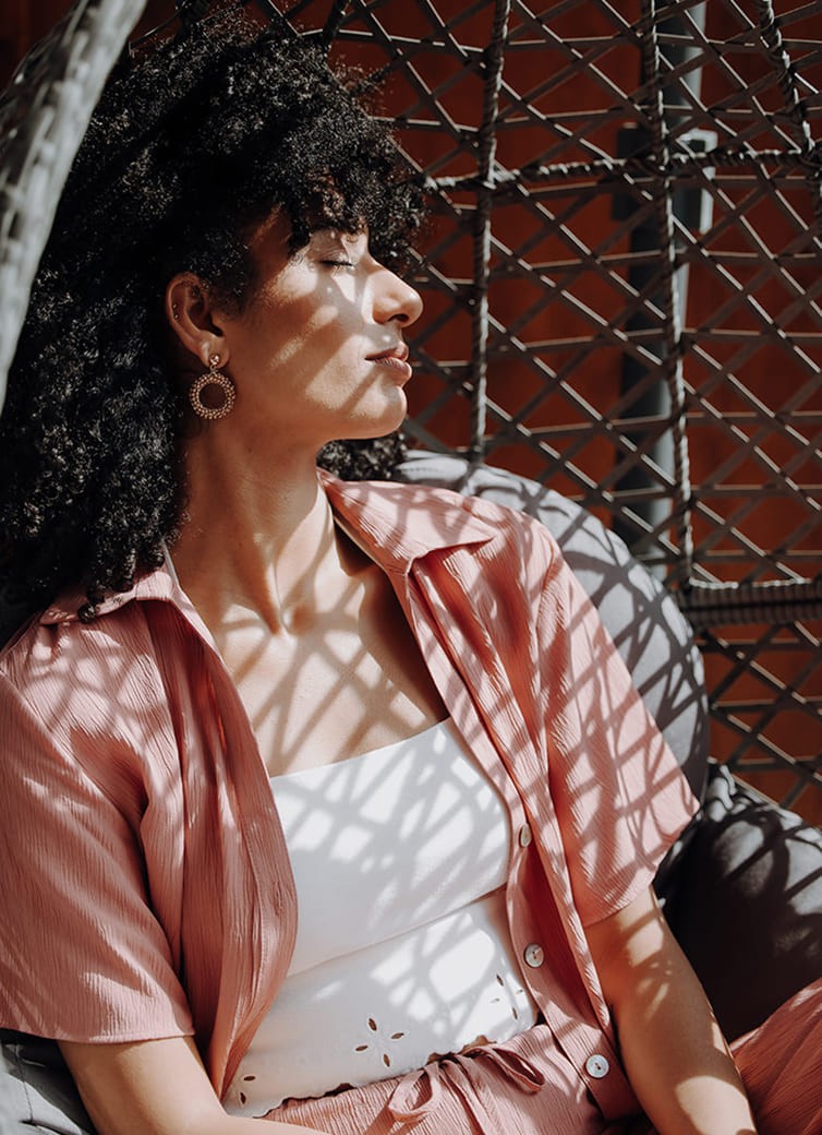 Person entspannt sich in einem h&auml;ngenden Korbstuhl und genie&szlig;t die Sonne